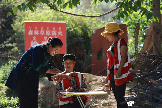 　　5月9日，全国人大代表、四川省凉山彝族自治州昭觉县庆恒村党支部书记吉克石乌（左）在村口森林草原防火检查点查看进出人员登记情况。新华社记者 江宏景 摄