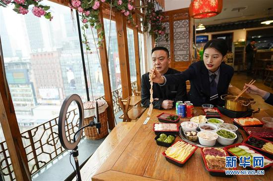 　　3月13日，重庆小天鹅火锅标准化生鲜火锅外卖的门店内，企业员工在抖音上进行推广直播。 新华社记者 刘潺 摄