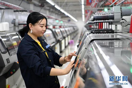 在甘肃省临夏回族自治州东乡族自治县城南区易地扶贫搬迁安置小区的扶贫车间，马八苦热在制衣车间工作（8月4日摄）。新华社记者 范培珅 摄