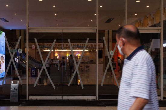 　　2023年7月16日，香港，一名男子走过一家购物中心，购物中心为了预防即将到来的台风“泰利”，在玻璃上贴上“米字胶”。