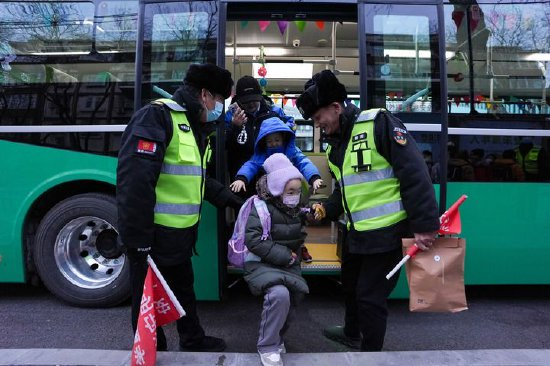 北京公交集团通学368路车停靠在呼家楼中心小学终点站,工作人员引导小学生下车(2024年12月16日摄)。新华社记者 鞠焕宗 摄