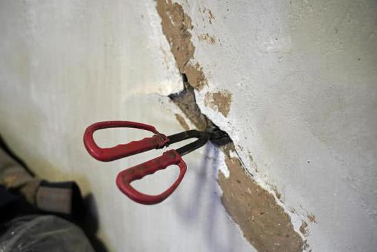 火钳在裂缝中可以轻易捅出墙外。