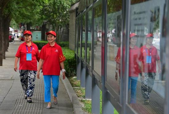 　　2015年7月12日，北京，“西城大妈”孟大妈（左）和丁大妈准备去居委会所在的胡同巡逻。视觉中国 资料图