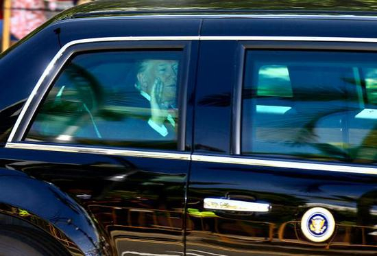 　　美国总统特朗普在自己的专车内向外招手。此次新加坡之行，是他首次到访，除了会见李显龙和金正恩，他没有户外参访活动。