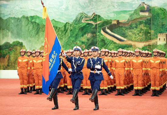 这是仪仗队员护卫着中国消防救援队队旗正步行进。新华社记者 李涛 摄