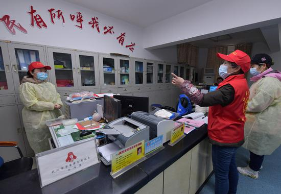 　　武汉市永清街道沈阳社区干部（右二）在社区办公室为同事分配工作任务（2月12日摄）。新华社记者 李贺 摄