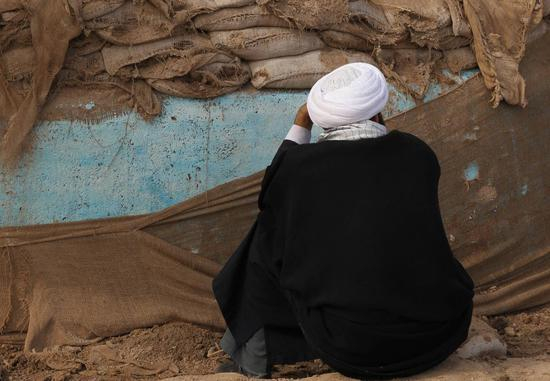 这位老人或许在那次战争中失去了亲人，久久静默于此。