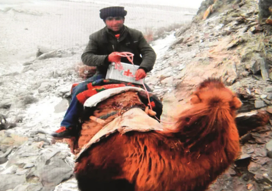 新疆塔什库尔干塔吉克自治县达布达尔乡，热斯喀木村村医发尔亚特·塔西白克骑着骆驼在山区巡诊。