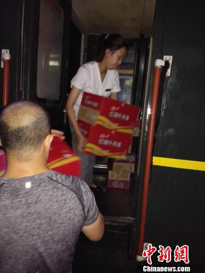 图为工作人员将食品送上滞留的列车，保证列车供水供食不断。　慕岩 摄