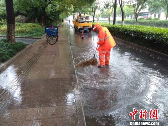 图为：环卫工人打扫积水路面。杭州市城管委供图