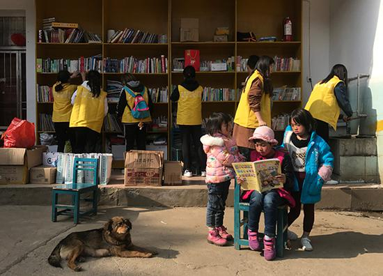 3月22日，志愿者帮忙整理书籍，几个彝族孩子在看书。澎湃新闻记者 张维 图