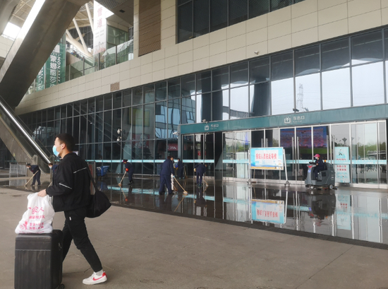 ▲4月5日，武汉站内的工作人员正在用水冲洗地面。新京报记者 李桂 摄