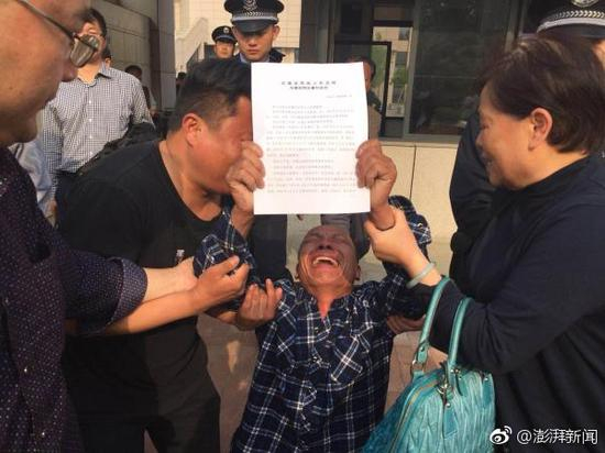 4月11日，周在春举着判决书走出法院，泣不成声。