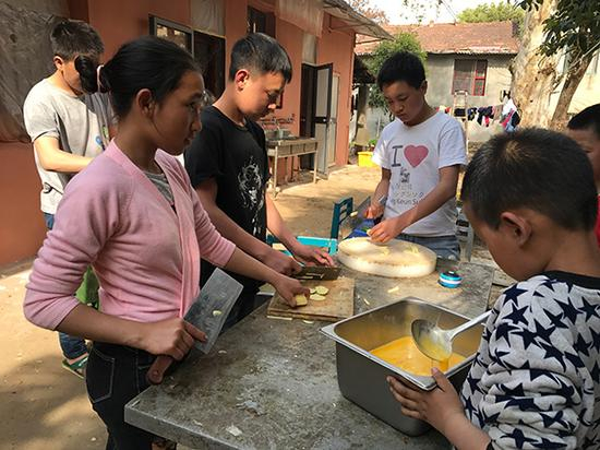 3月28日，安么木扎（左一）和孩子们一起帮厨。澎湃新闻记者 张维 图