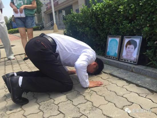 ▲获无罪后，廖海军在法院门前朝父母遗像磕头告慰。新京报记者 赵凯迪 摄