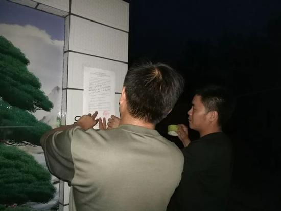 图：包村乡镇干部晚上张贴村两委换届相关公告