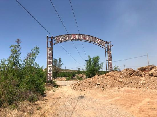 5月22日，爱心村后门的路已经被土堵住，牌坊破旧不堪。新京报记者王翀鹏程摄