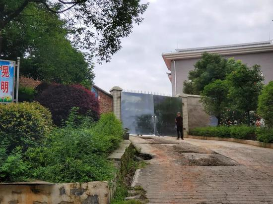 　　6月21日，新晃一中操场正在挖掘尸体，大门紧锁，不时有人站在门口往里观望。新京报记者 李云蝶 摄