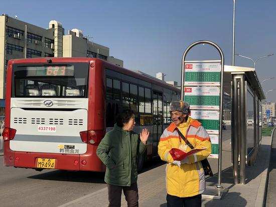 站前广场前的“上地东街中路”公交站，志愿者给旅客指路。新京报记者 周依 摄