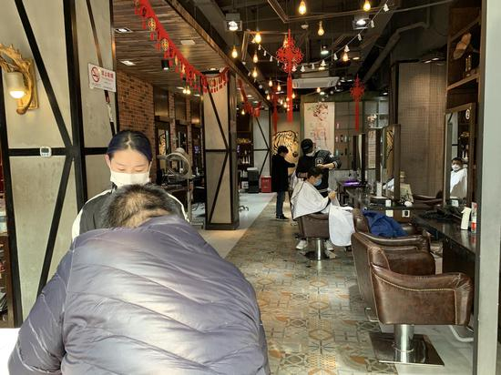 浦东一理发店店内有空座，为限流让客人在外等，进门需登记信息量体温。澎湃新闻记者 陈逸欣 图