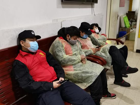 中午时分，社区志愿者们坐在社区办公室的长椅上打盹。