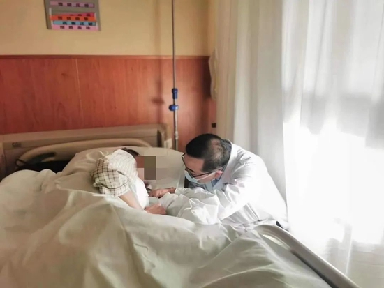 ▲安宁疗护病房内，路桂军蹲在患者床前交谈。受访者供图