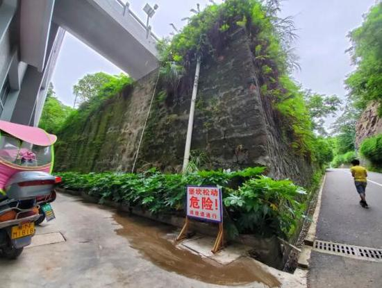 　　6月22日，新晃一中通往跑道的路旁设置了“堡坎松动危险！请绕道通行”的危险提示牌。 新京报记者 李云蝶 摄