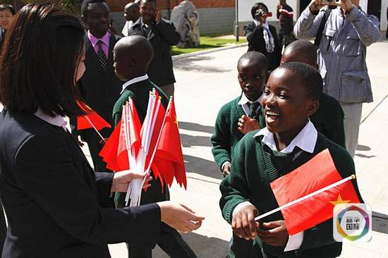 　　2012年6月26日，一名津巴布韦小学生在中国驻津大使馆举行的“开放日”活动上接过中国国旗，并学说“你好”。（新华社记者许林贵摄）