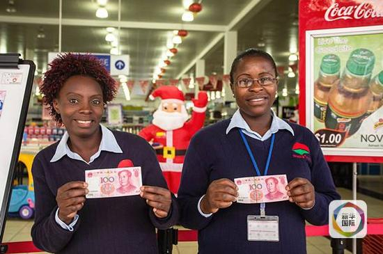 　　2015年11月19日，在津巴布韦首都哈拉雷一家超市前，两名售货员拿着人民币摆拍。（新华记者许林贵摄）