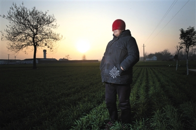 　　60岁的艾滋病感染者林梅（化名）站在田地里，笑着，她的身后，夕阳正好。