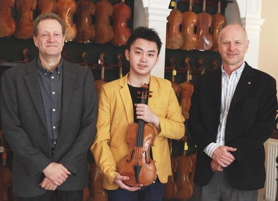 何子毓从J&A Beare琴行老板Steven Smith和Simon Morris手中接过斯特拉迪瓦里小提琴。（J&A Beare）