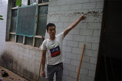 位男子指着墙上约2米高的水迹线
