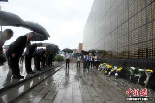 震后40年，海外侨胞唐山访亲，雨中向大地震纪念墙献花。（中新社记者 翟羽佳 摄）