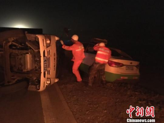 图为消防营救人员正在大风中搜寻被困人员。 买吾拉 摄