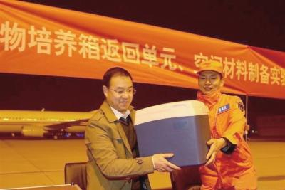 　　11月18日，在北京西郊机场，空间应用系统副总设计师吕从民(左)从西安卫星测控中心回收部总工程师冀刚(右)手中接过高等植物培养箱返回单元和空间材料制备实验样品。