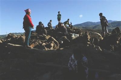 　　缅甸过来的边民跑到土堆上观看对面缅甸境内山头交火的情况。刚刚发射的炮弹在空中留下一个烟雾圈。 图据东方早报