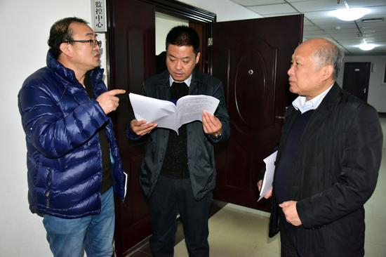 2016年12月31日晚，胡建森在新乡市环保局走廊里部署第二天的执法检查。摄影/章轲