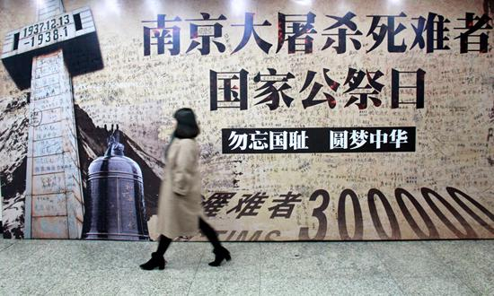 2016年12月12日，南京，市民从地铁站的“国家公祭日和平许愿墙”边经过。 视觉中国供图