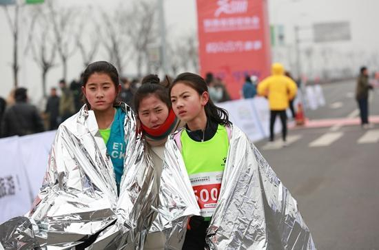 1月15日，3个女孩在西安一场冬季马拉松赛后披着保暖的金属披风。视觉中国供图