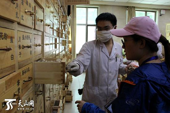 自治区中医医院药房工作人员，正在给来访的2017年“新疆速度·全国网络媒体新疆行”记者讲解药房相关情况。