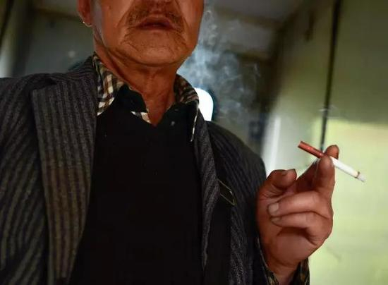 资料图：一位乘客在两节车厢中部抽烟。