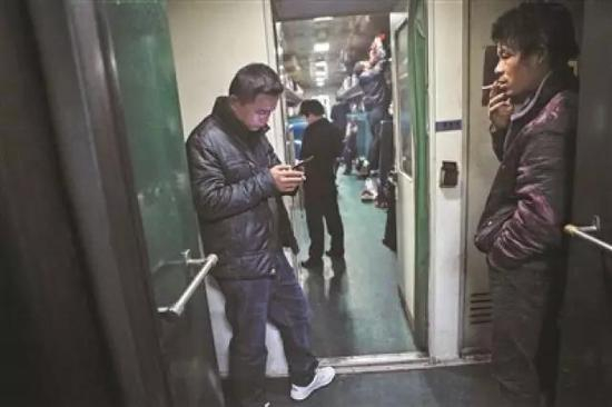 乘客在普通列车的车厢连接处抽烟