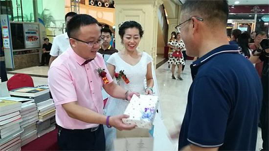 　　来宾们手里拿着精心挑选的一本书，扉页上写着祝福的话语。一对新人弯腰接过，回赠来宾的也是一本在扉页上写着奋进共勉的文字。