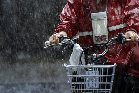 2017年8月23日，广州，台风“天鸽”带来降雨，一外卖员骑行在雨中。视觉中国 图