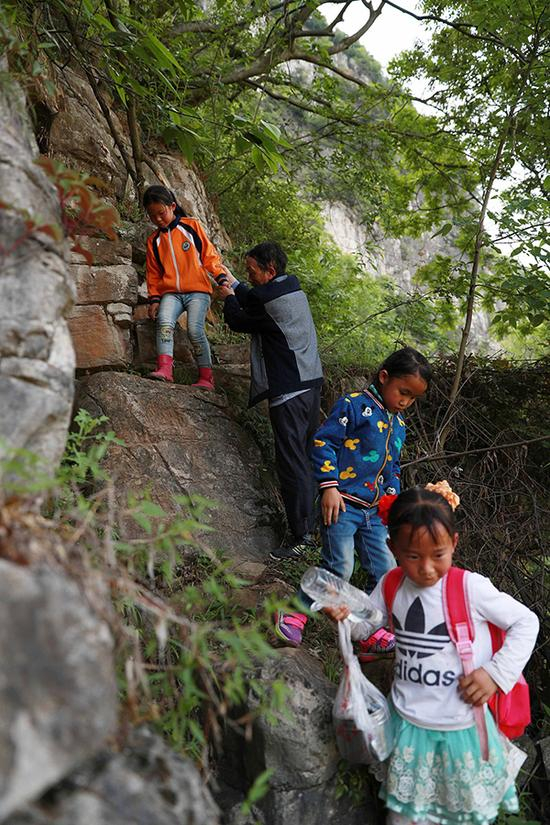 杨绍书在崎岖的山路上接学生上学。 视觉中国 资料图