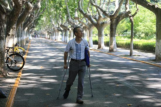 周义仓教授拄拐走在校园里。 视觉中国 图