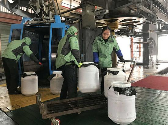 在索道上缆车点工作人员正在运送打包的粪便。