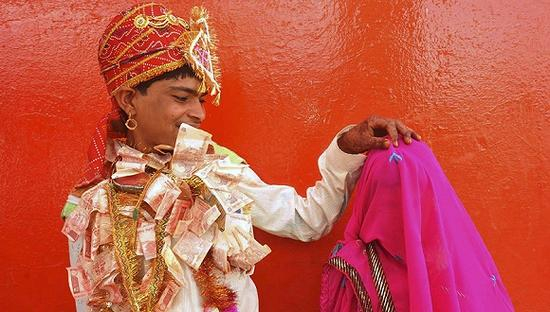  2011年5月，在印度拉治加，14岁的Bablu戴着钞票做的花环准备揭开12岁新娘Mata Bai的盖头。图片来源：东方IC