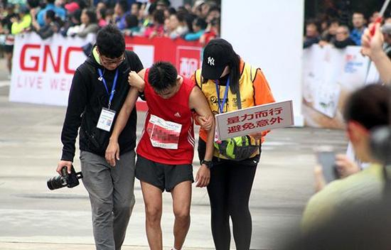 2015年上海国际马拉松赛，志愿者搀扶力竭跑友。 &nbsp;东方IC 资料图