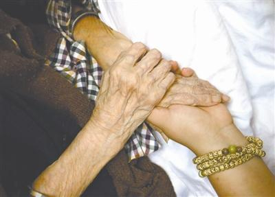 董伟握着一位临终老人的手。皮肤的接触，能让老人感受到温暖和关怀。